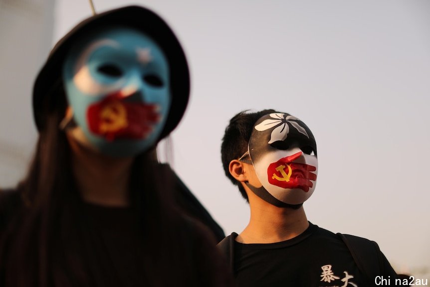 Two protesters wear masks with the Hong Kong, Commusit party and East Turkestan symbol on them.