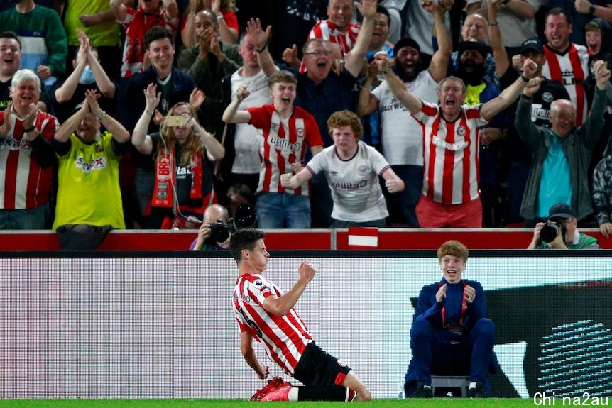 Brentford player Christian Norgaard slides on his knees in front of fans during a Premier League game against Arsenal.