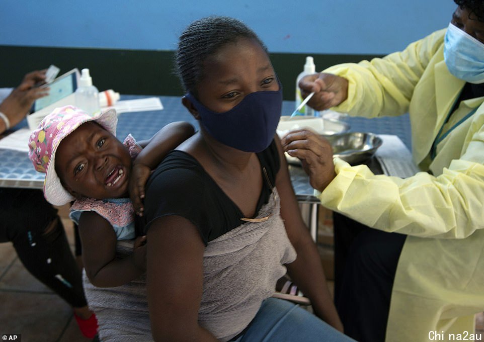 A baby cries as her mother receives her Pfizer vaccine against COVID-19, in Diepsloot Township near Johannesburg, South Africa