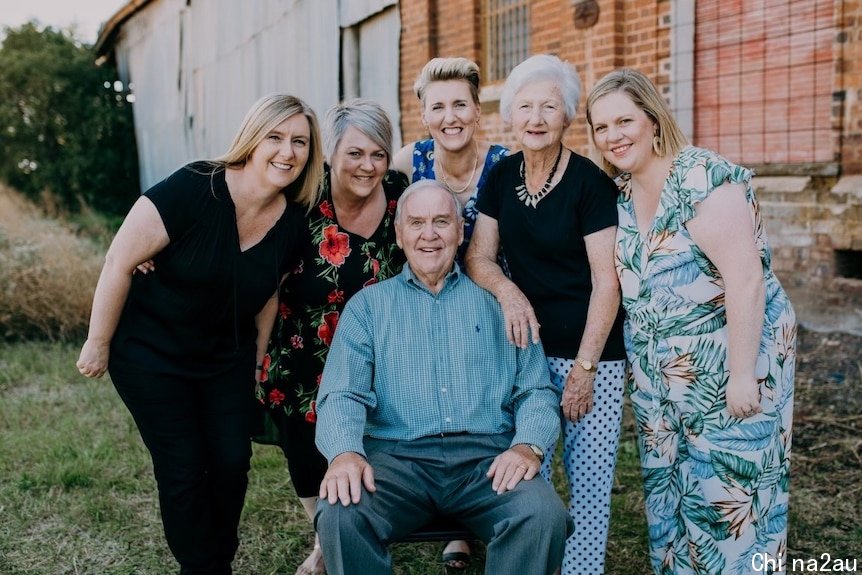 A seated man surrounded by 5 standing women