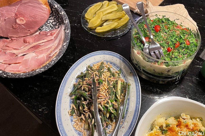 A table of Christmas spreads including salad and ham.