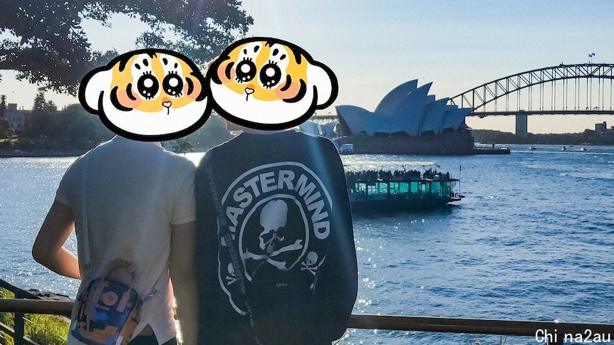 Two men standing together with the Sydney Harbour Bridge in the background (their faces are not shown).