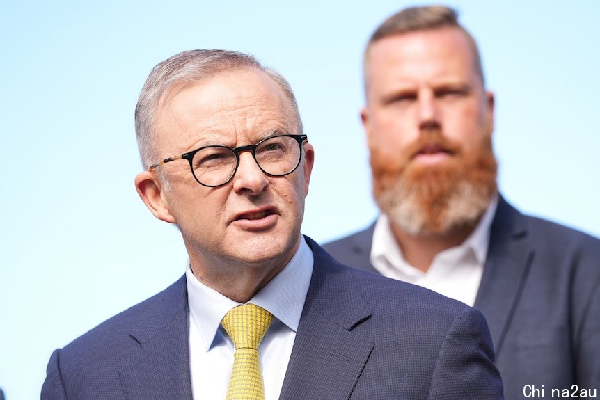 Anthony Albanese in focus wearing a suit and yellow tie and Hunter candidate Dan Repacholi standing behind him