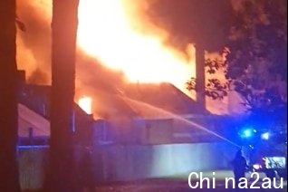 A firefighter shoots water from a hose onto a raging structure fire