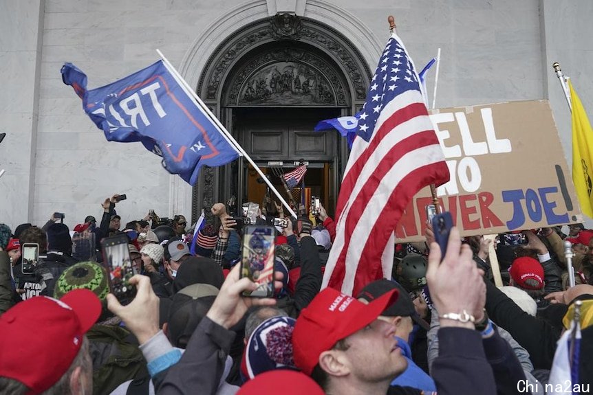 Rioters in the US hold up American flags outside the Capitol building 