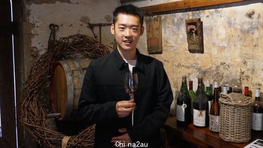 A man holds a wine glass at a winery.