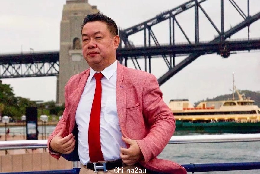 A man in a pink suit stands in front of the Sydney Harbour Bridge.