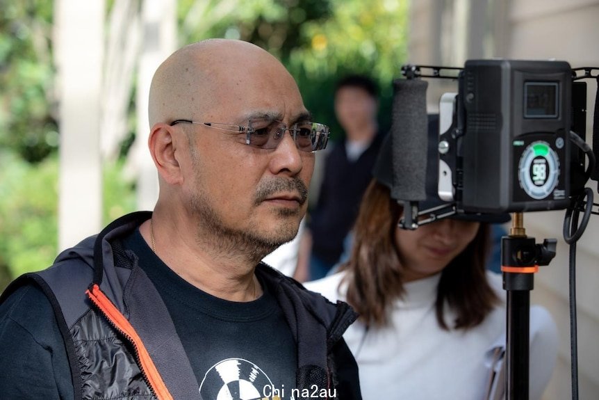 An Asian man looking at a TV monitor at a filming set