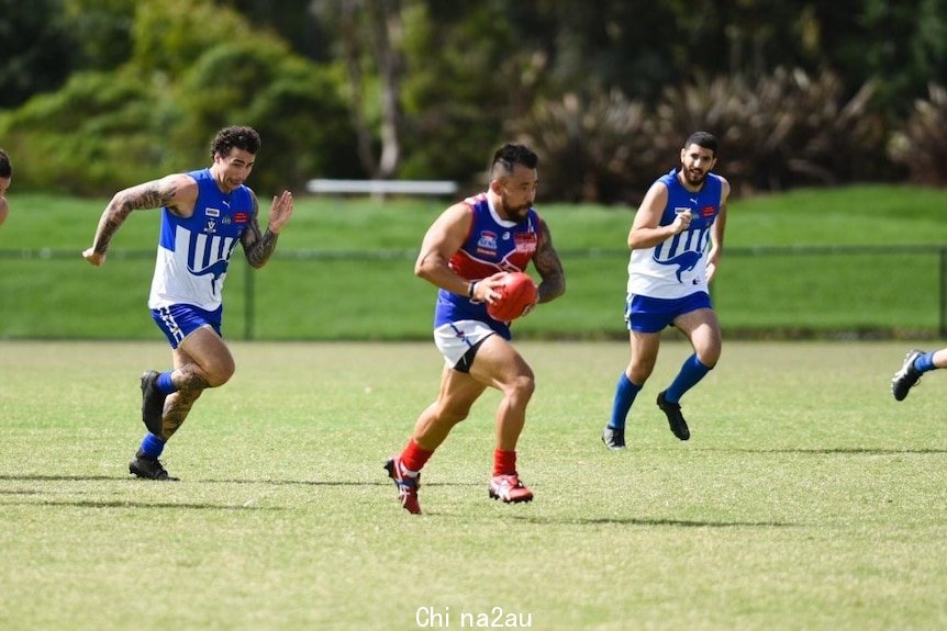 An Asian man playing Aussie rules.