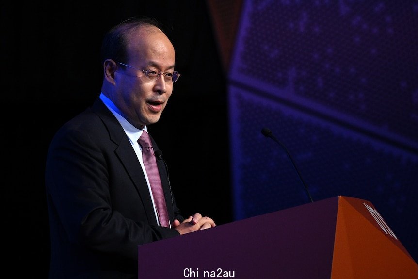 Xiao Qian speaks from a podium at an event. 