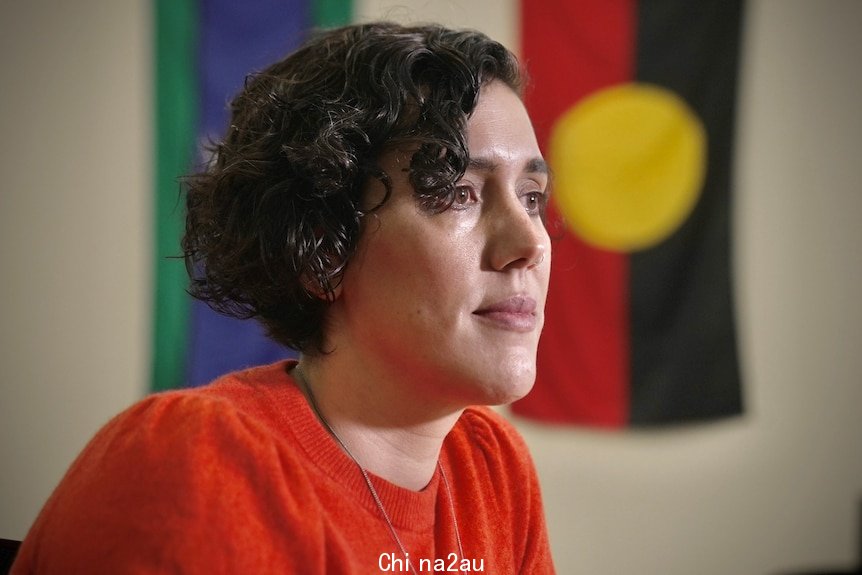 A woman wears a red shirt sitting in a room.