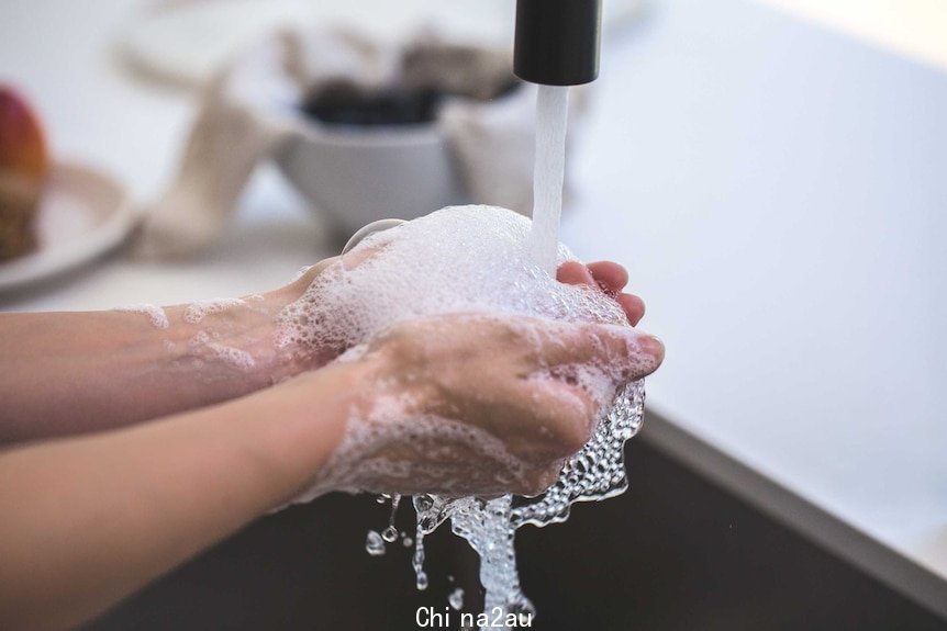 A person washes their hand at a sink.