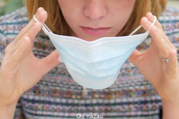 Close-up of woman's face and hands putting on a mask during the coronavirus pandemic in Australia.