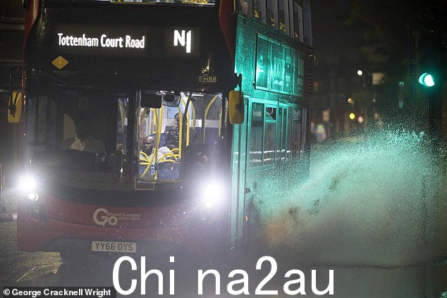 伦敦东南部格林威治遭遇暴雨和雷暴后，一辆巴士驶过部分被淹没的道路