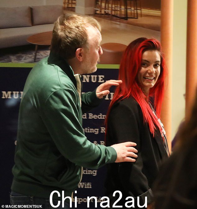 黛安·巴斯韦尔 (Dianne Buswell) 与克里斯·麦考斯兰 (Chris McCausland) 一起进入酒店时笑容满面